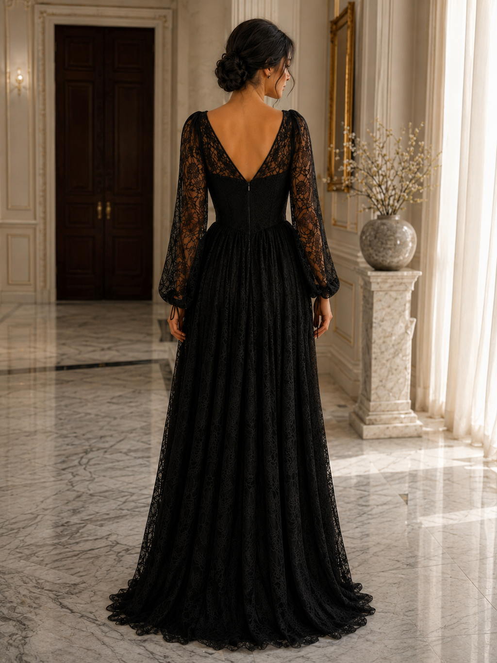 A woman wearing a floor-length black lace evening gown with sheer long sleeves and a deep V-neckline, photographed from the back in an elegant indoor hallway with marble floors and cream walls.

