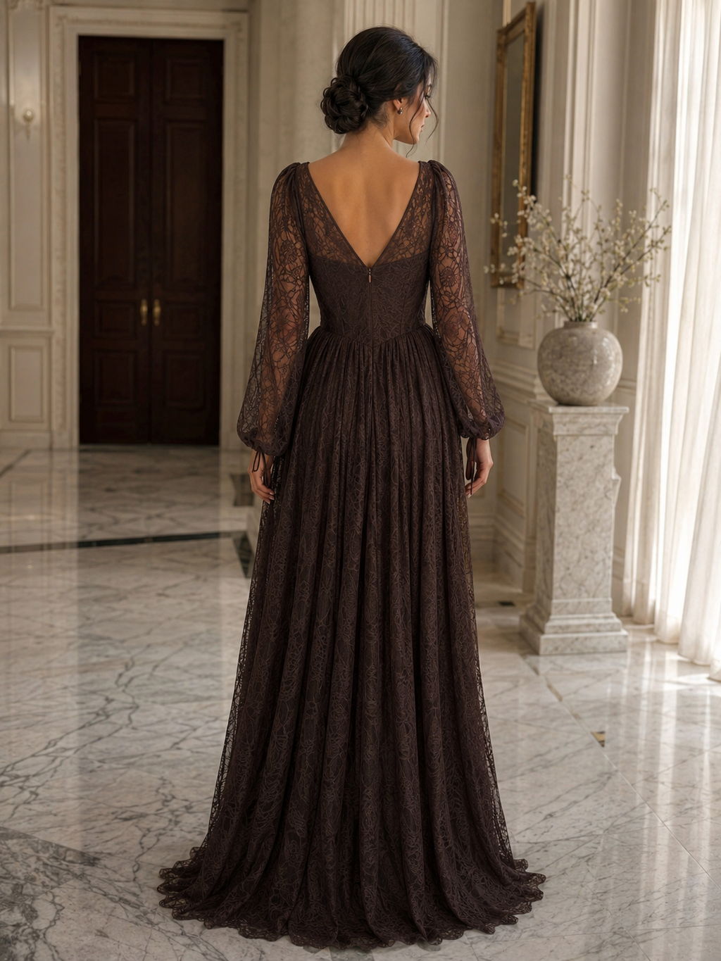 A woman wearing a floor-length dark brown lace gown, shown from the back in an elegant indoor hallway with marble floors and a stone pillar.

