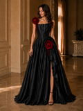 Woman wearing a black evening gown with red floral accents in an elegant indoor setting.

