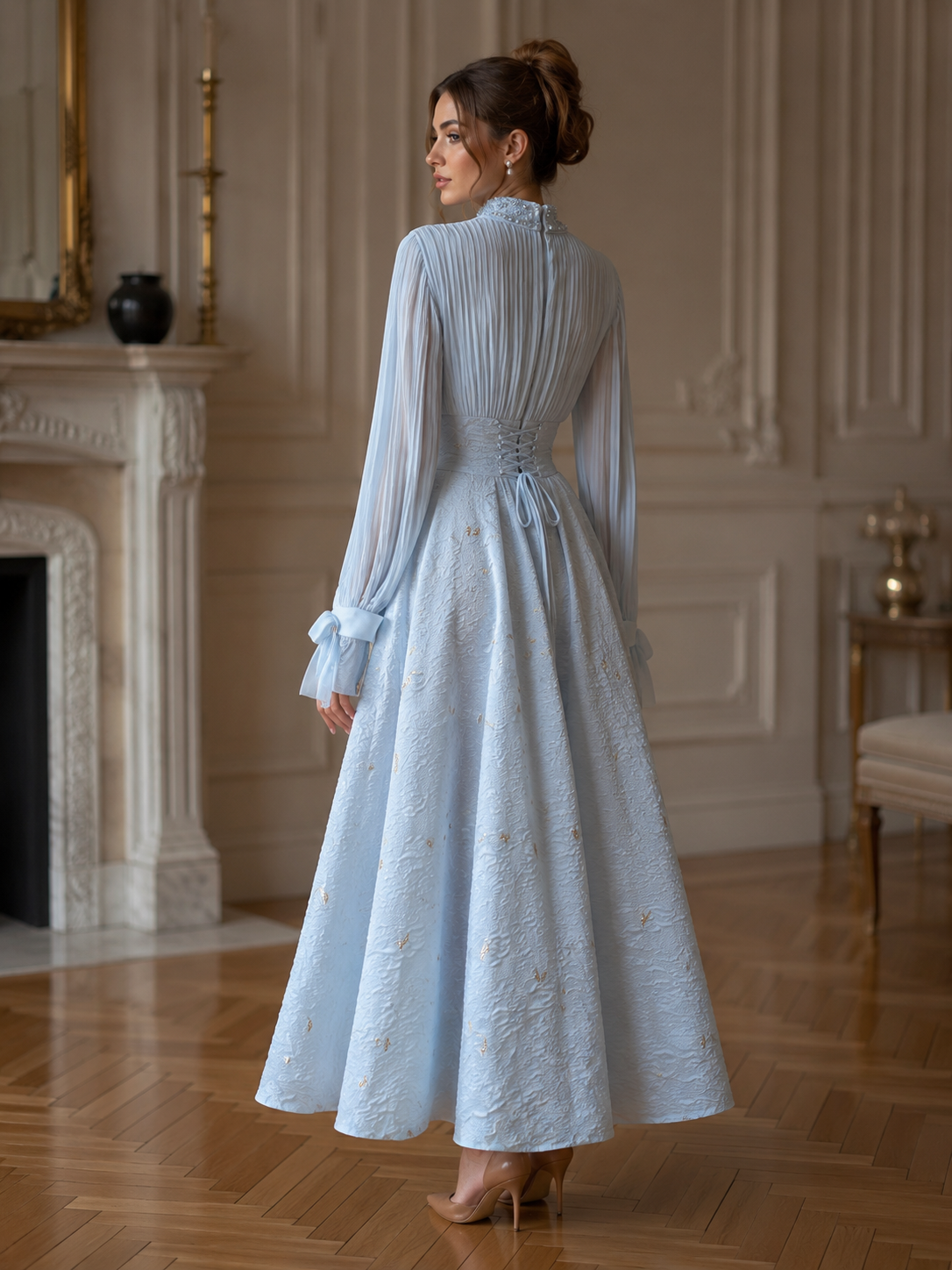 Back view of ice blue A-line evening dress with lace-up corset waist, pleated back bodice, long sleeves, and textured gold motif skirt
